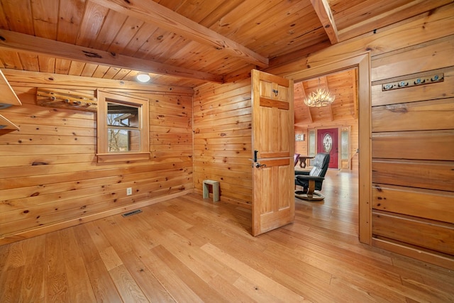 spare room featuring beamed ceiling, a wealth of natural light, and light hardwood / wood-style flooring