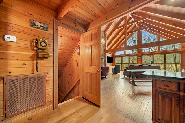 interior space with wooden walls, high vaulted ceiling, wooden ceiling, beamed ceiling, and light wood-type flooring