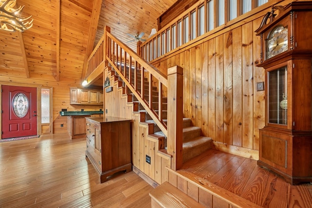 stairs featuring wood walls, high vaulted ceiling, wooden ceiling, hardwood / wood-style flooring, and beam ceiling