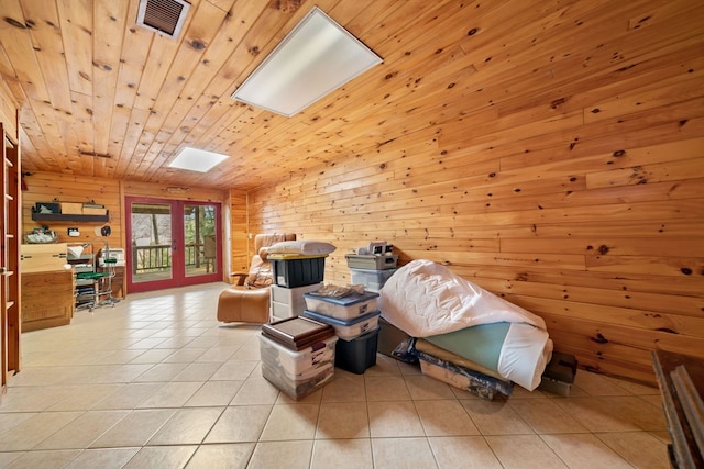 sitting room with wooden walls, a skylight, light tile patterned floors, wooden ceiling, and french doors