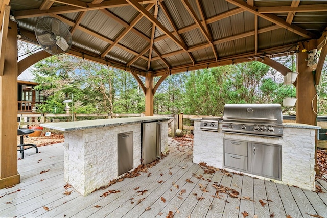 deck with a gazebo, an outdoor kitchen, ceiling fan, and grilling area