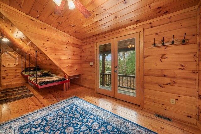 bedroom with wooden walls, hardwood / wood-style flooring, access to outside, wood ceiling, and french doors