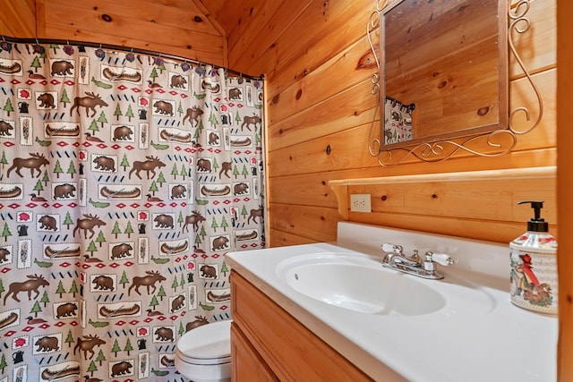 bathroom with vanity, a shower with curtain, wooden walls, and toilet