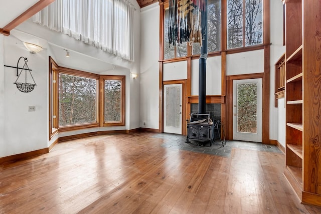 198 Hollow Log Trl, Ellijay, GA 30536 - unfurnished living room featuring a towering ceiling, hardwood / wood-style floors, a wood stove, and baseboards