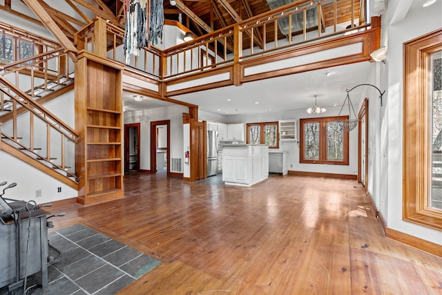 198 Hollow Log Trl, Ellijay, GA 30536 - unfurnished living room featuring a chandelier, baseboards, wood-type flooring, stairway, and a high ceiling