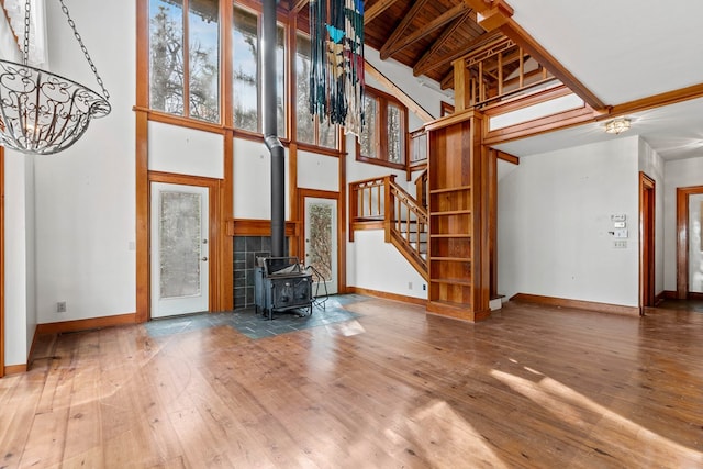 198 Hollow Log Trl, Ellijay, GA 30536 - unfurnished living room with baseboards, stairs, hardwood / wood-style flooring, a towering ceiling, and a wood stove