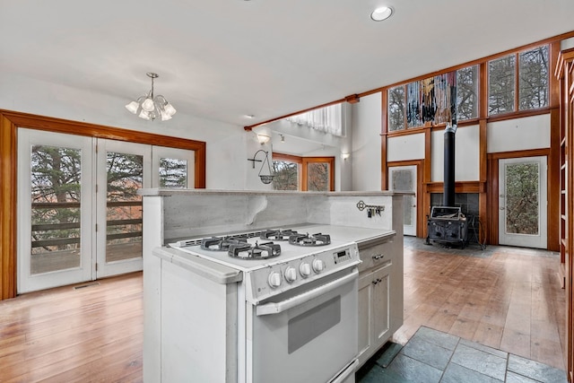198 Hollow Log Trl, Ellijay, GA 30536 - kitchen featuring white range with gas cooktop, backsplash, a chandelier, light countertops, and a wood stove