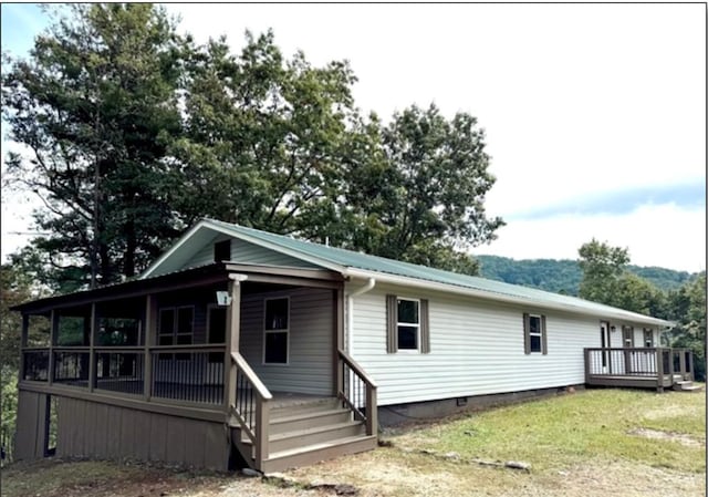 view of front of home featuring crawl space, covered porch, a front lawn, and metal roof