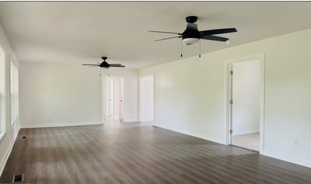 spare room featuring dark wood-type flooring, visible vents, ceiling fan, and baseboards