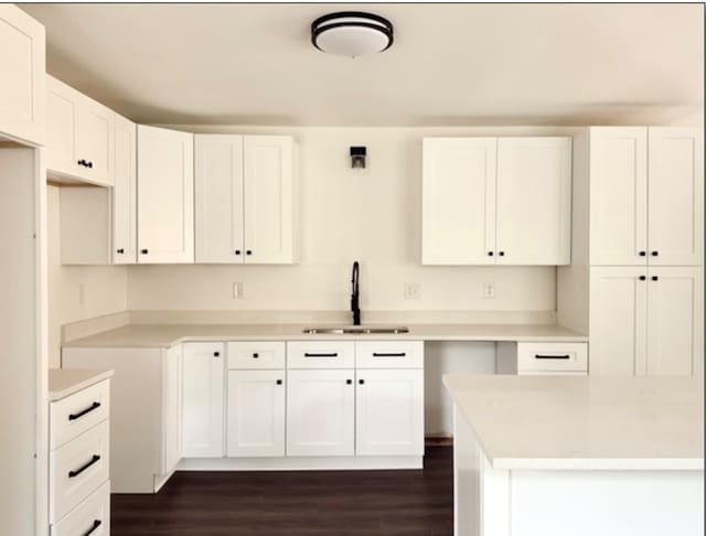 kitchen featuring dark wood-style floors, white cabinetry, light countertops, and a sink