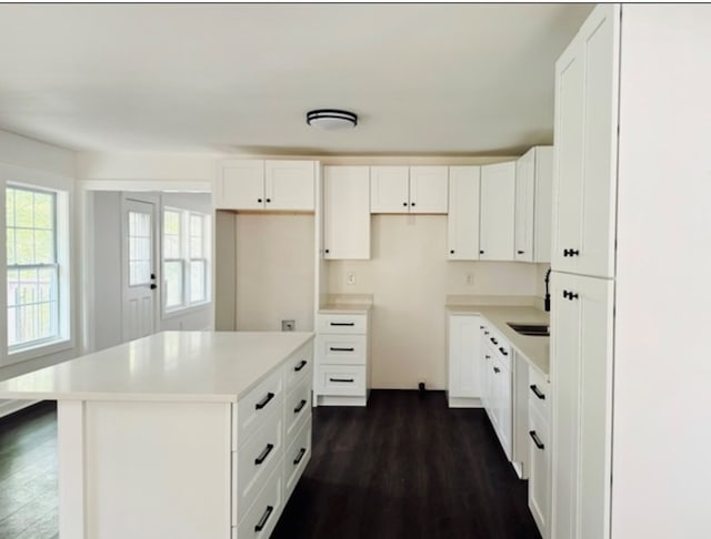 kitchen featuring light countertops, dark wood-type flooring, a center island, and white cabinets