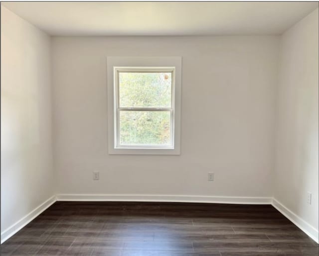 spare room featuring dark wood-style flooring and baseboards