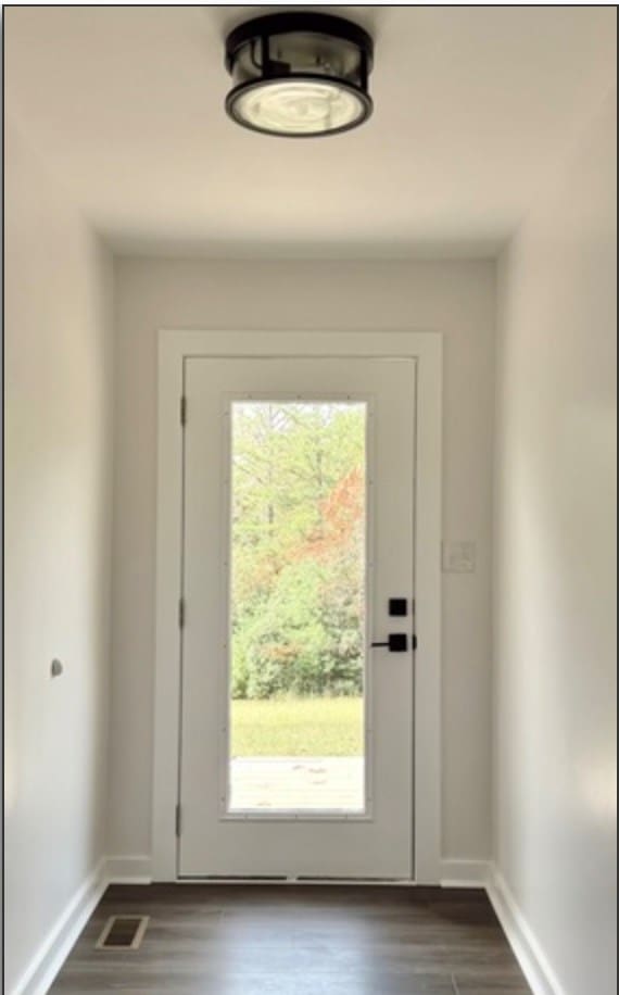 doorway with dark wood-style floors, baseboards, visible vents, and a healthy amount of sunlight