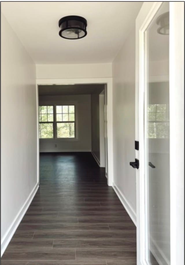 hallway featuring baseboards and dark wood finished floors