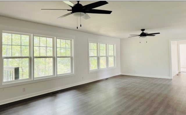 empty room featuring a ceiling fan, baseboards, visible vents, and dark wood-style flooring