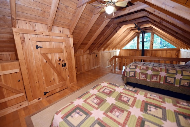 bedroom featuring wooden walls, vaulted ceiling, and wood finished floors