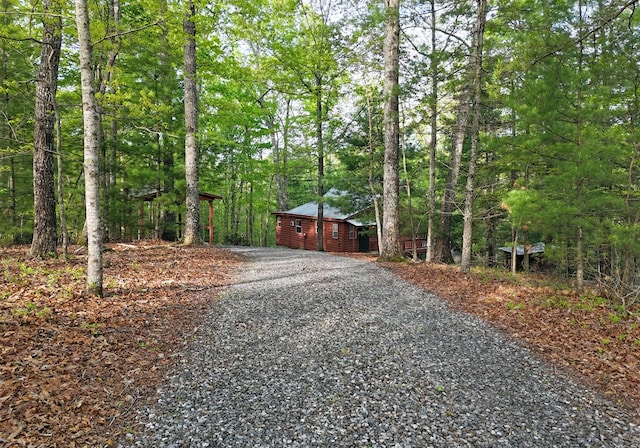 exterior space featuring gravel driveway and a view of trees