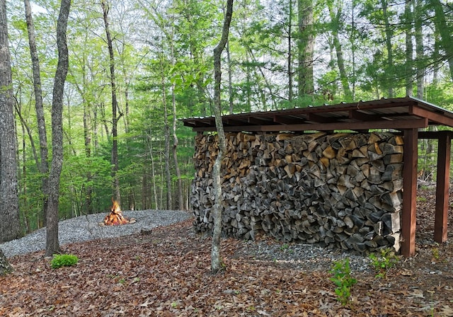 view of outbuilding with a fire pit and a forest view