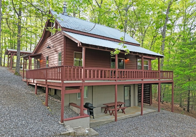 rear view of house featuring metal roof, a deck, stairway, and a patio area