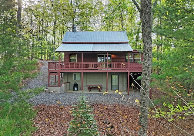 rear view of property with stucco siding, a deck, a patio area, and metal roof