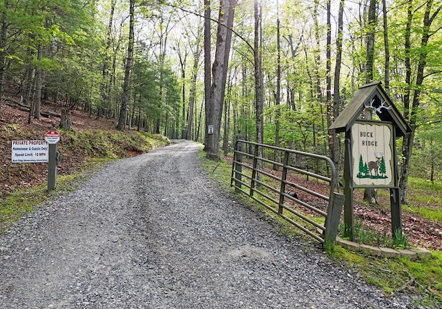 view of road featuring a gated entry and a wooded view