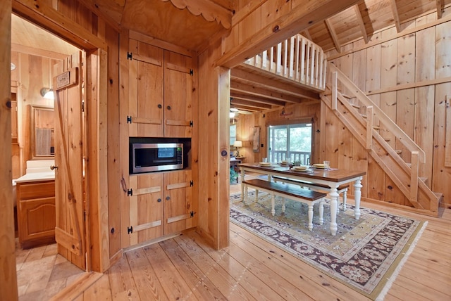 dining area featuring wooden walls, wood ceiling, and light wood-style floors