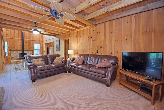 living area with a wood stove, wood walls, beam ceiling, and hardwood / wood-style floors