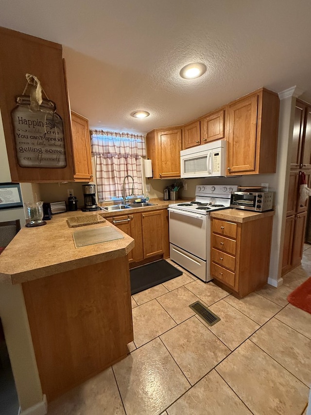 kitchen with white appliances, sink, light tile patterned floors, a textured ceiling, and kitchen peninsula