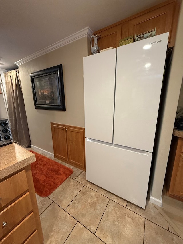 kitchen featuring light tile patterned floors, white refrigerator, and crown molding