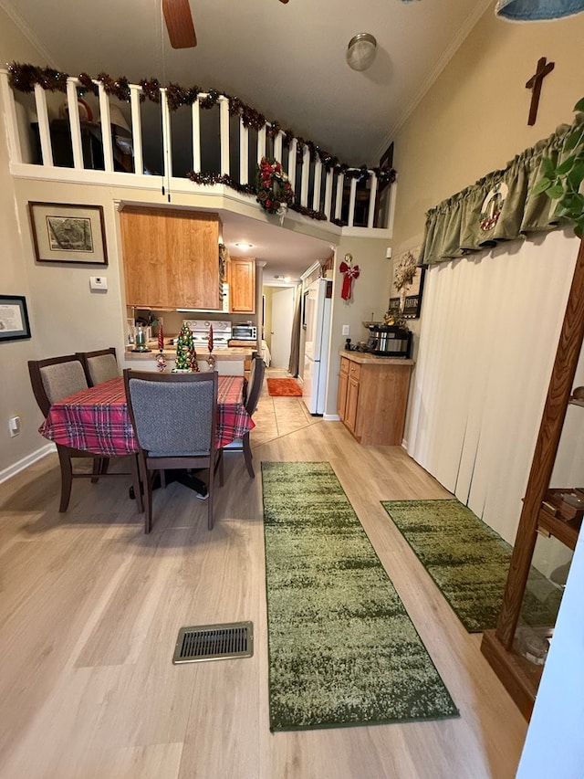 dining space with crown molding, ceiling fan, and light wood-type flooring