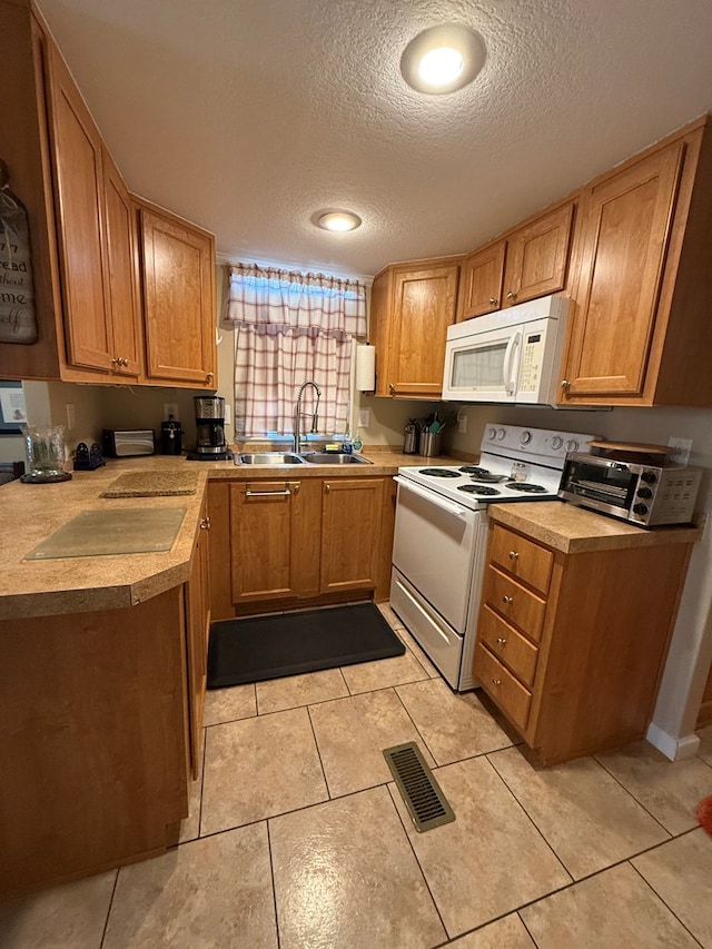 kitchen featuring a textured ceiling, sink, light tile patterned floors, and white appliances