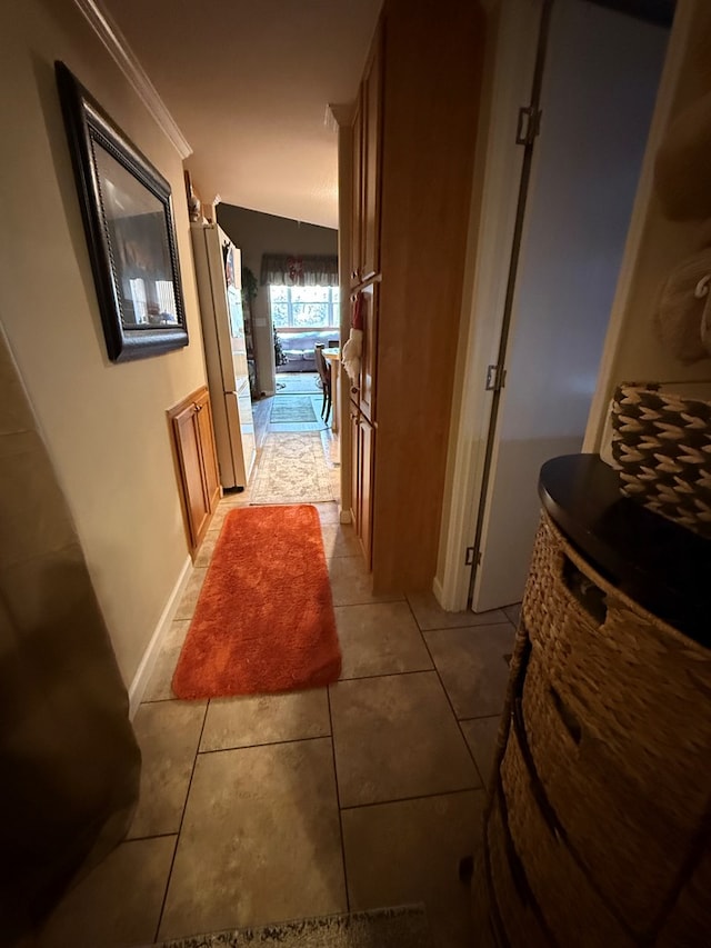 hallway with light tile patterned floors and crown molding