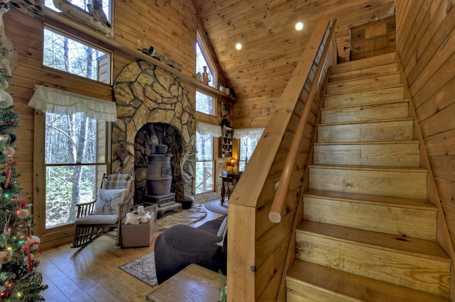 stairs featuring high vaulted ceiling, a healthy amount of sunlight, a wood stove, and hardwood / wood-style flooring