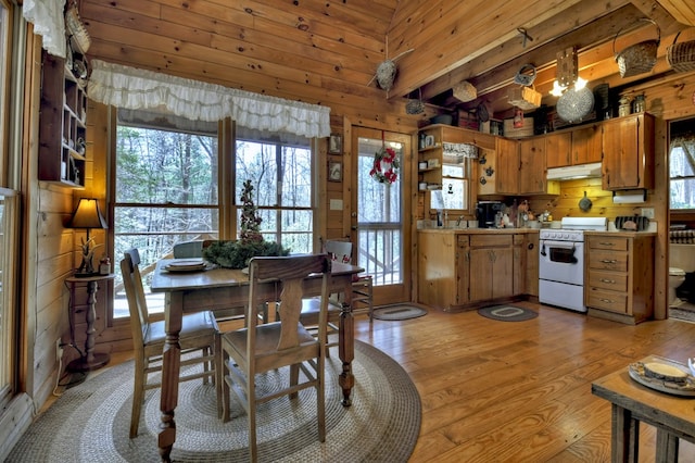 dining room featuring a wealth of natural light, wood walls, and light wood-style floors