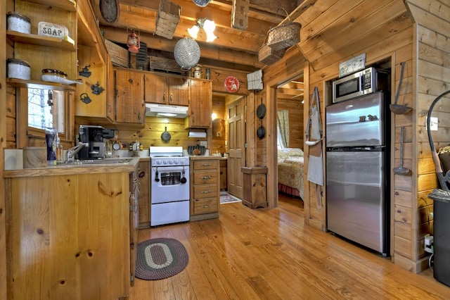 kitchen with light wood finished floors, under cabinet range hood, light countertops, white range oven, and freestanding refrigerator