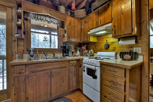 kitchen with brown cabinetry, electric range, a sink, light countertops, and under cabinet range hood