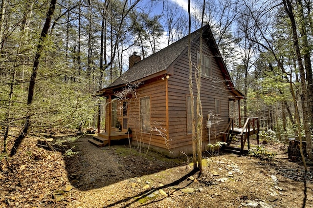 view of side of property with roof with shingles and a chimney