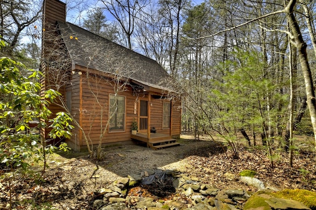 exterior space featuring roof with shingles and a chimney