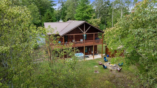 rear view of property featuring a deck, metal roof, a forest view, and a patio area