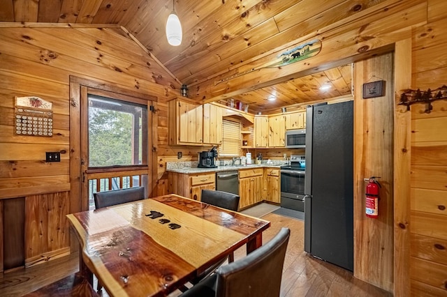 kitchen featuring stainless steel appliances, wood walls, and light countertops