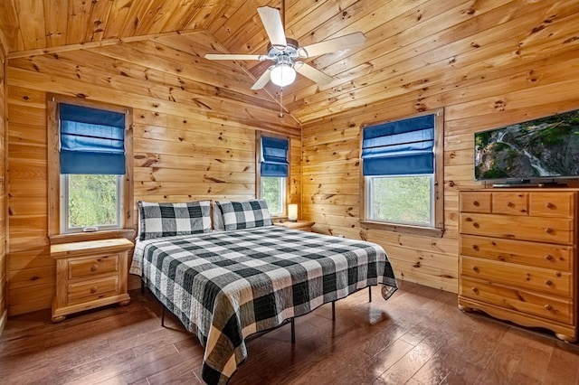 bedroom featuring wood walls, multiple windows, vaulted ceiling, and hardwood / wood-style floors