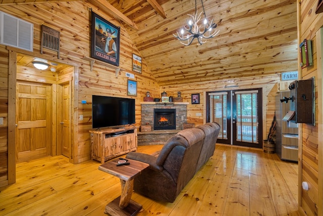 living room with wood walls, high vaulted ceiling, a fireplace, and light hardwood / wood-style floors