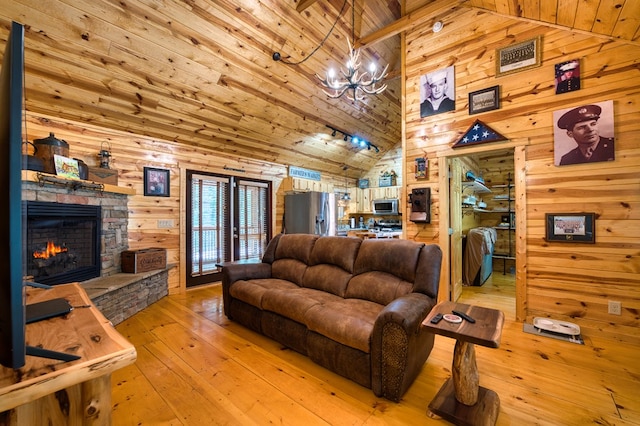 living room featuring wood ceiling, light hardwood / wood-style flooring, a stone fireplace, and wooden walls