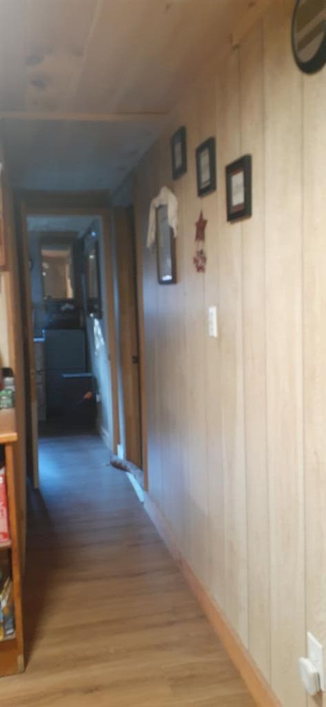 hallway with wooden walls and wood-type flooring