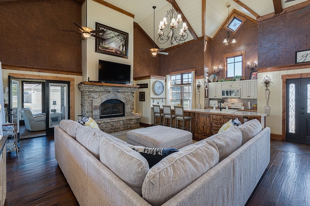 living room with a stone fireplace, high vaulted ceiling, dark hardwood / wood-style flooring, and ceiling fan with notable chandelier