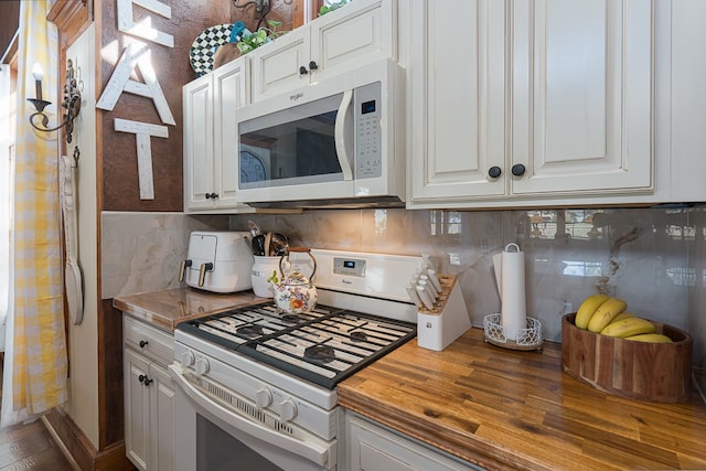 kitchen with butcher block countertops, backsplash, hardwood / wood-style flooring, white cabinets, and white appliances