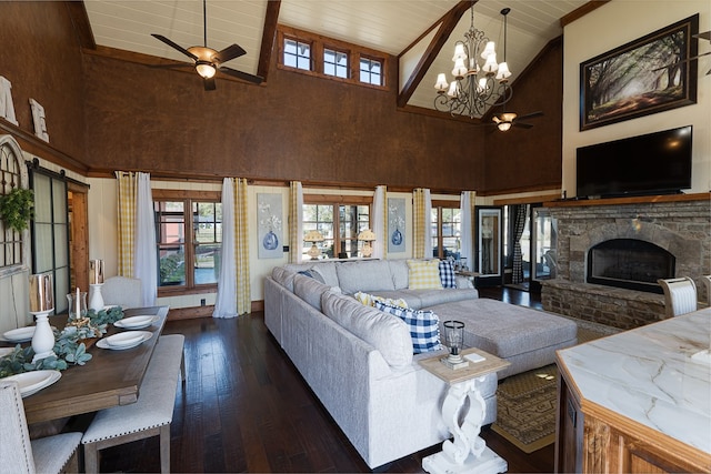 living room with dark wood-type flooring, a fireplace, ceiling fan with notable chandelier, and high vaulted ceiling