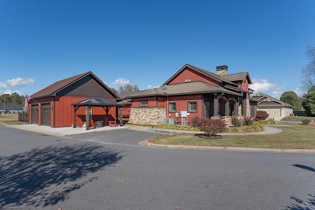 view of front of home with a garage, a front lawn, and a gazebo