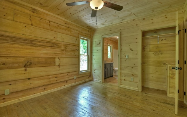 unfurnished room with ceiling fan, light wood-style flooring, wooden ceiling, wood walls, and baseboards
