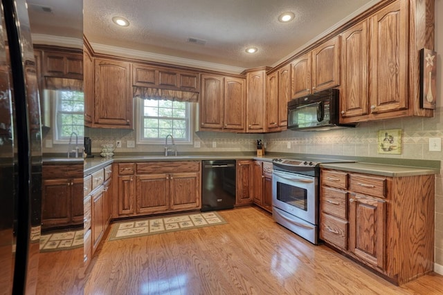 kitchen with visible vents, a sink, light wood finished floors, and black appliances